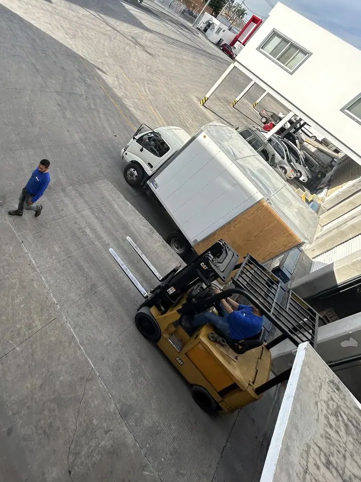 Vista desde arriba del patio de Mubit: un montacargas amarillo acerca carga a un camión de caja