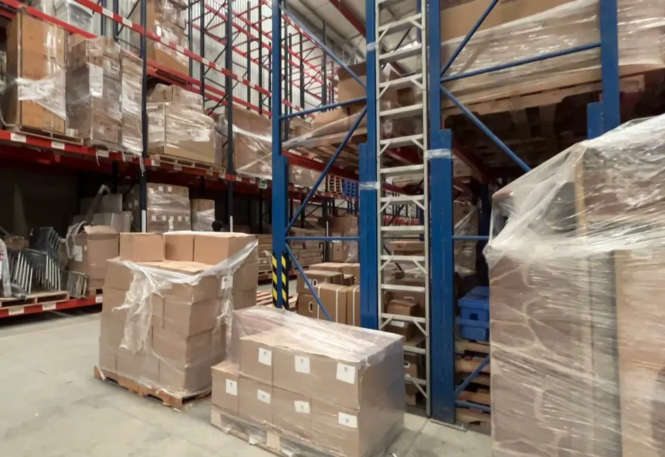 Tarimas de cajas con película plástica frente a los racks del almacén